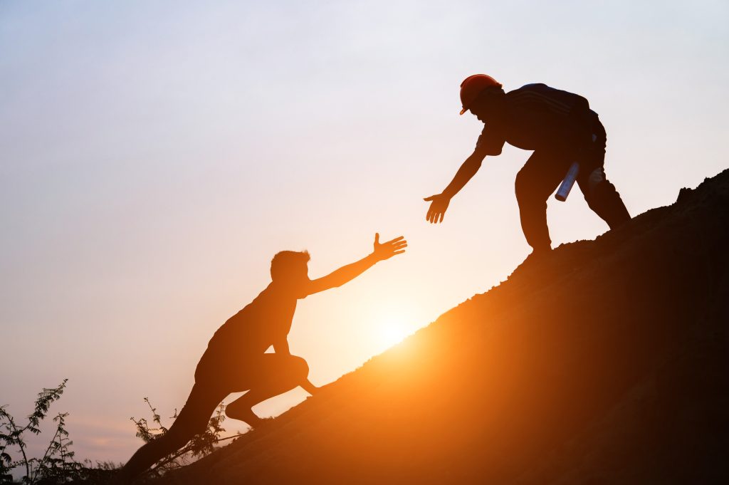 team building motivacija, dvojica kolega pomažu jedan drugom na uzbrdici