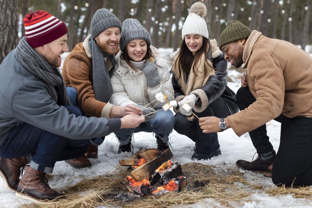 petoro kolega sede oko logorske vatre u snegu 
